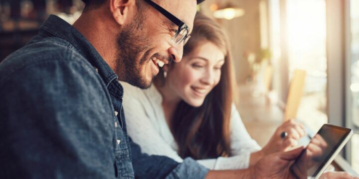 A man and woman looking at an ipad.