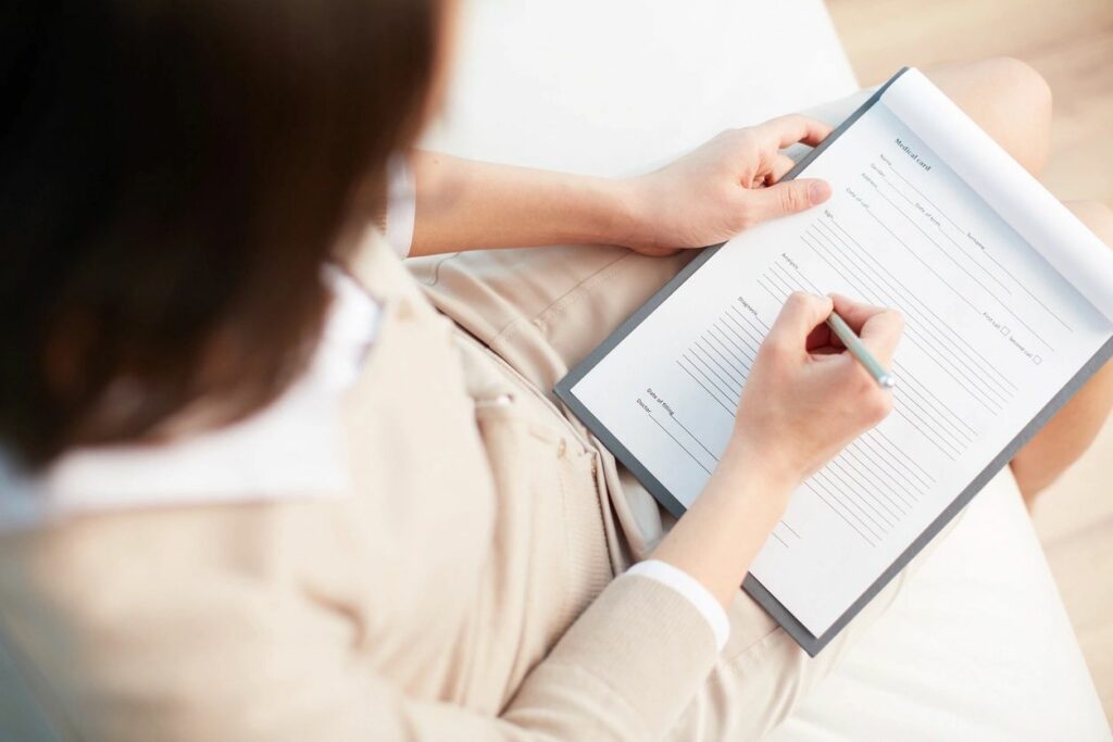 A person writing on paper with pen and tablet.